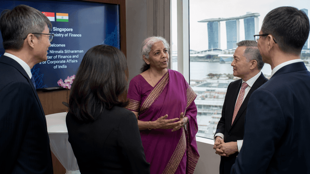 Finance Minister Nirmala Sitharaman stands in a room in Singapore, speaking with government representatives.