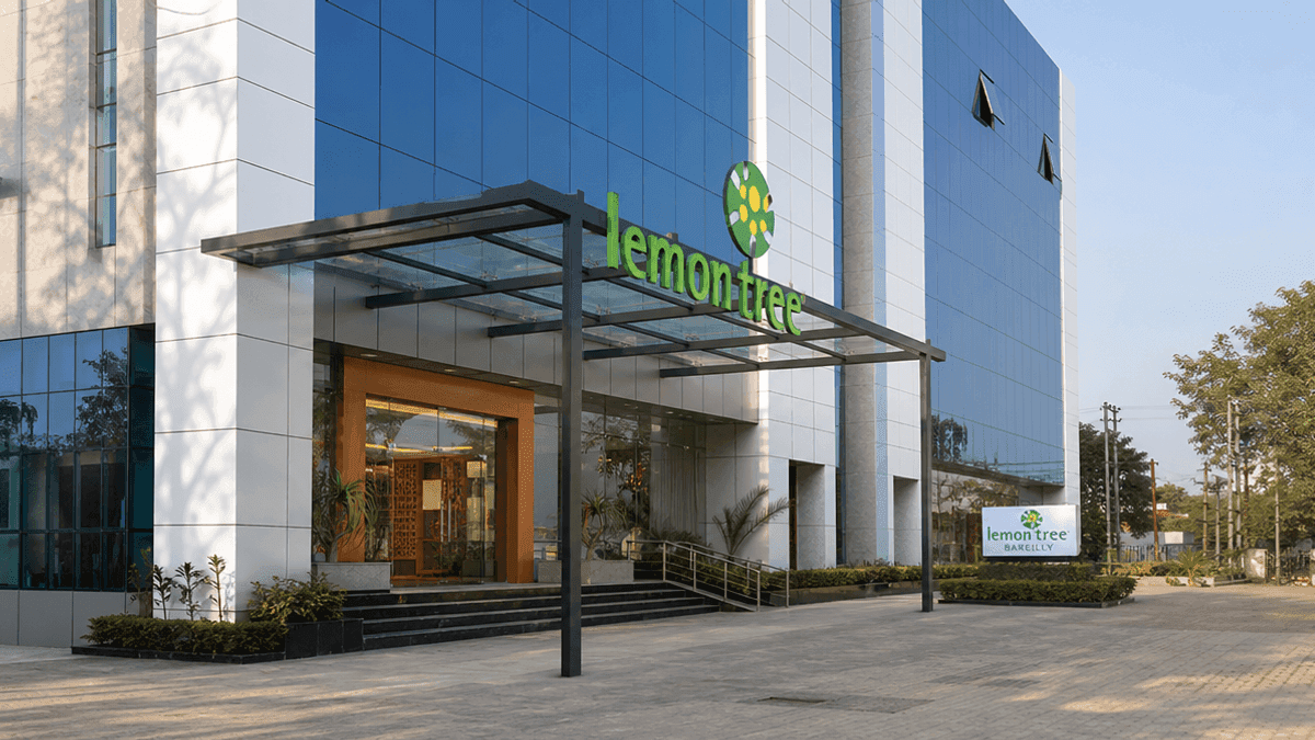 A hotel building exterior with a glass facade and an entrance, representing a Lemon Tree hotel property.