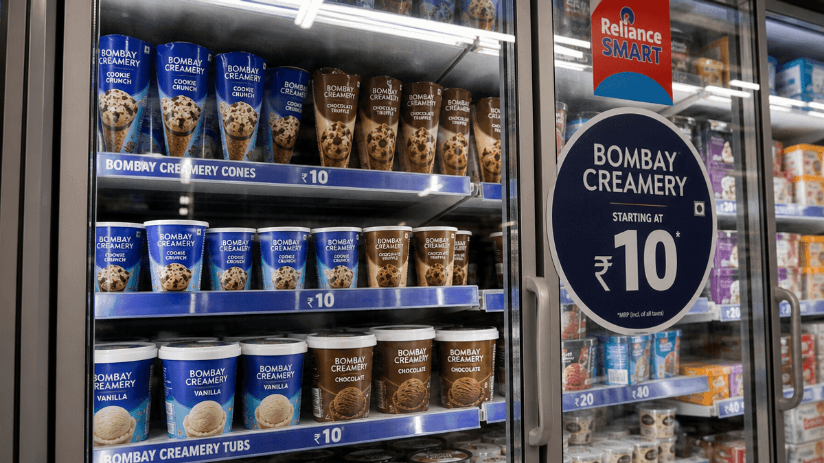 A freezer aisle in a store showing Bombay Creamery ice cream cones and tubs with a price tag of ₹10 on the glass.